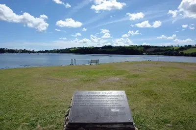 a bench in a field next to a body of water at Regatta Cottage in Feock