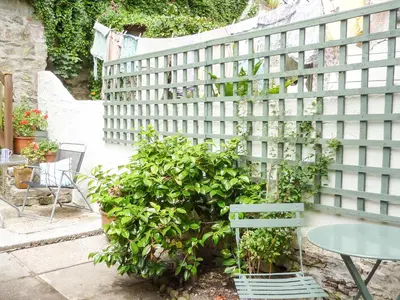 a green fence with a table and a plant at Quarry Cottage in Flushing