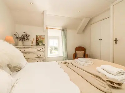 a bedroom with a white bed with towels on it at Evergreen in Breage