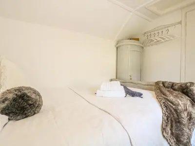 a cat laying on a white bed in a room at Evergreen in Breage