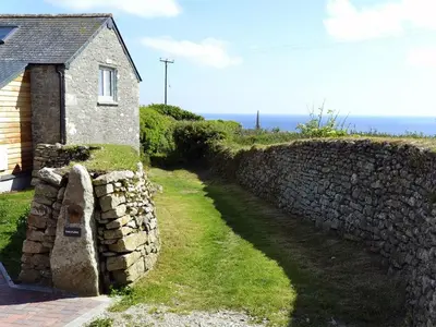 a stone wall next to a house and a building at The Studio in Germoe