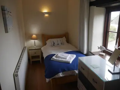 a small bedroom with a bed and a desk at Talehay Cottages in Looe