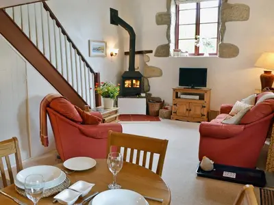 a living room with a table and chairs and a fireplace at Chywood Barn in Carleen