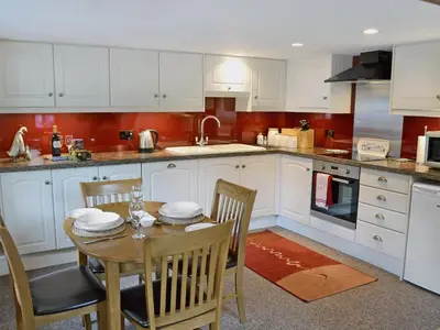 a kitchen with white cabinets and a table and chairs at Chywood Barn in Carleen
