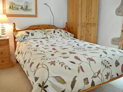 a bedroom with a bed with a floral comforter at Chywood Barn in Carleen
