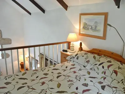 a bedroom with a bed and a lamp and a staircase at Chywood Barn in Carleen
