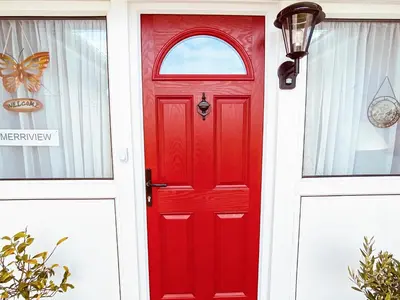 a red door with a window on a white house at Merriview in Germoe