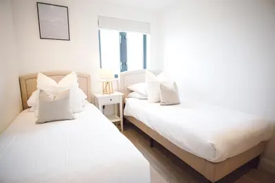 two beds sitting next to each other in a bedroom at Stunning Two Bed Sea View Apartment with Pool & Gym in Newquay