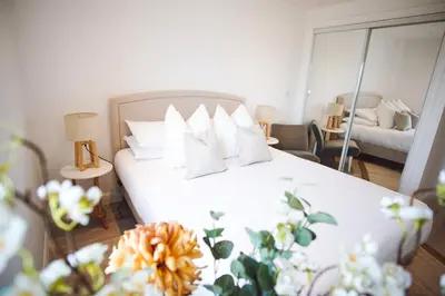 a bedroom with a white bed with pillows and a mirror at Stunning Two Bed Sea View Apartment with Pool & Gym in Newquay