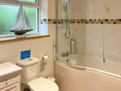 a bathroom with a toilet and a sailboat on a window at Swallows Rest in Doublebois