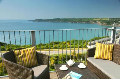 a balcony with two chairs and a table and the ocean at Porth Avallen Hotel in St Austell