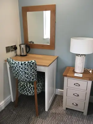 a desk with a chair and a mirror and a lamp at The Pityme Inn in Wadebridge