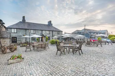 a patio with tables and chairs in front of a building at The Jamaica Inn, Bodmin, Cornwall - The Coaching Inn Group in Bolventor