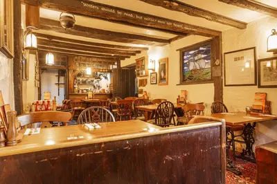 a restaurant with wooden tables and chairs and a bar at The Jamaica Inn, Bodmin, Cornwall - The Coaching Inn Group in Bolventor