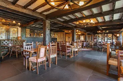 a restaurant with wooden tables and chairs in a room at The Jamaica Inn, Bodmin, Cornwall - The Coaching Inn Group in Bolventor