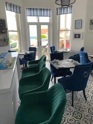 a restaurant with green chairs and tables and windows at Lazy Waves in Newquay