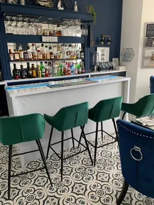 a bar with green chairs in front of a counter at Lazy Waves in Newquay