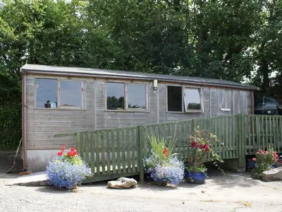 a tiny house with flowers in front of a fence at Badger Cottage in Mawgan