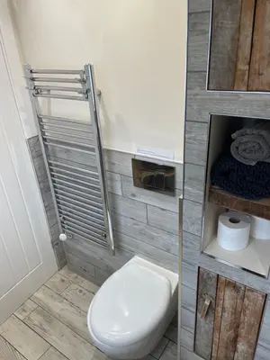 a bathroom with a white toilet and a towel rack at Little Fernleigh in Perranporth