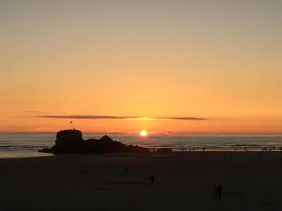 a sunset at the beach with people walking on the beach at Little Fernleigh in Perranporth