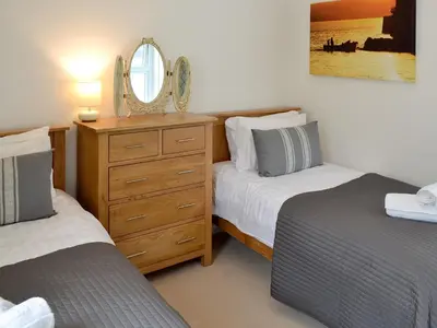 a bedroom with two beds and a dresser with a mirror at Seaglass in Marazion
