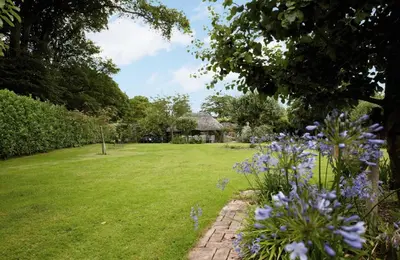 a garden with purple flowers and a house at Mews Cottage in Cury