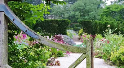 a wooden gate leading to a garden with flowers at St Corantyn Cottage in Helston