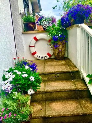 a set of stairs with flowers and a sign that saysower at Wellingtons in Fowey