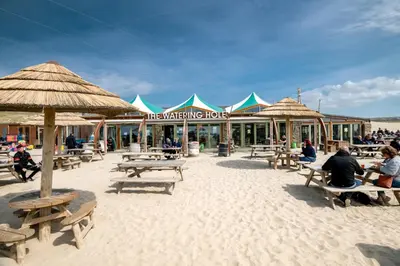 a beach with picnic tables and umbrellas on the beach at Lambriggan Court in Perranzabuloe