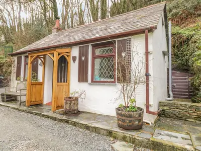 a small white cottage with a wooden door at Coachman's in Forrabury