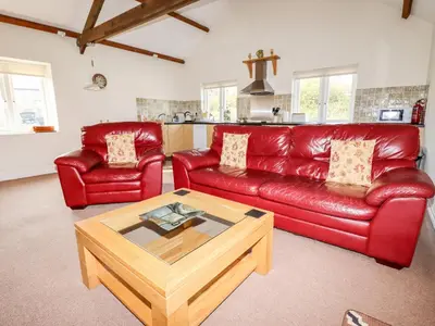 a living room with a red leather couch and a coffee table at Wheal Rose in Newlyn East