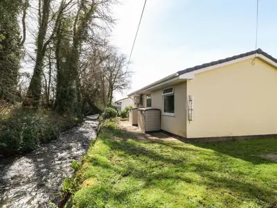 a small white house with a grass yard at 3 Rosecraddoc Lodge in Saint Cleer