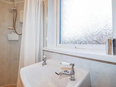 a white sink in a bathroom with a window at The Annexe, Laburnum in Bugle