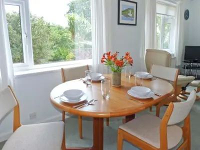 a dining room table and chairs with a wooden table and flowers at Joylands in Budock Water