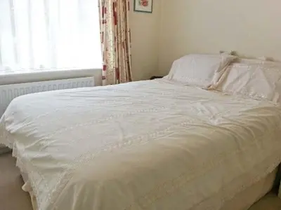 a white bed in a bedroom with a window at Joylands in Budock Water