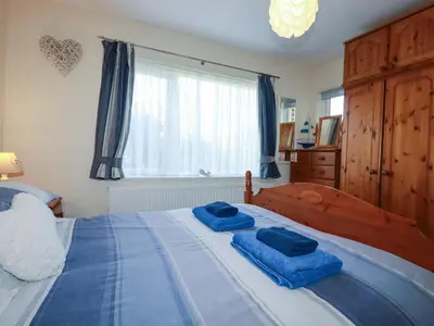 a bedroom with a large bed with blue towels on it at Summerfield Cottage in Gorran Haven