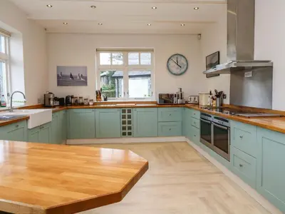 a kitchen with blue cabinets and a wooden table at Penarvon House in Helford