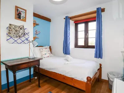 a bedroom with a bed and a desk and a window at 4 Mowhay Cottages in Saint Goran