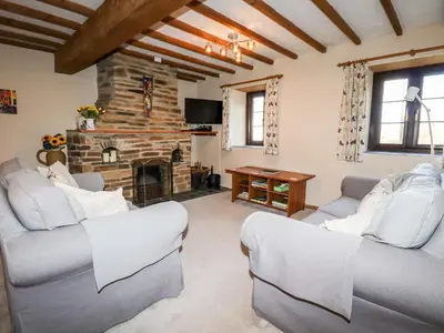 a living room with two couches and a stone fireplace at 4 Mowhay Cottages in Saint Goran