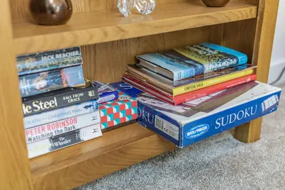 a stack of books sitting on a book shelf at The Litte Hideaway in Saint Columb Minor