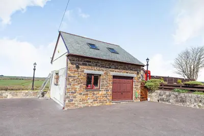 a small brick building with a red door at The Litte Hideaway in Saint Columb Minor