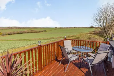 a wooden deck with a table and chairs on it at The Litte Hideaway in Saint Columb Minor