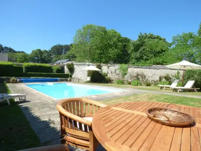 a wooden table and chairs next to a swimming pool at The Bullshed in Saint Erth