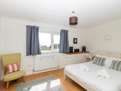 a bedroom with a bed and a chair and a window at Seaport Lodge in Mawgan Porth