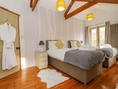 a bedroom with two beds and a door with a mirror at Woodfield Coach House in Merrymeet