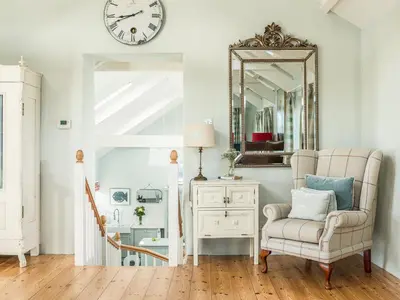 a living room with a chair and a mirror at The Barn at Little Resugga in Bugle