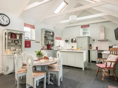 a kitchen with a table and chairs and a clock at The Barn at Little Resugga in Bugle