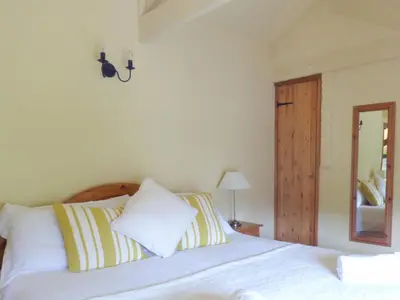 a bedroom with a bed with white sheets and a mirror at Old Winery Cottage in Golant