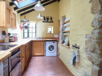 a kitchen with a washer and dryer on the wall at Old Winery Cottage in Golant
