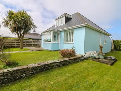 a blue house with a stone wall in a yard at Bolenowe in Polzeath